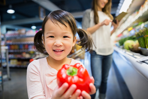 Girl with red pepper in grocery store
